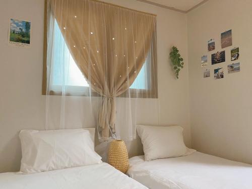 a bedroom with two beds and a window with curtains at TheComma in Seoul