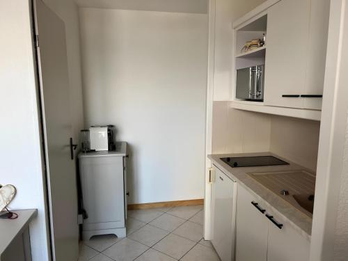 a kitchen with white cabinets and a refrigerator at Appartement centre Saint Gervais-Vue imprenable in Saint-Gervais-les-Bains