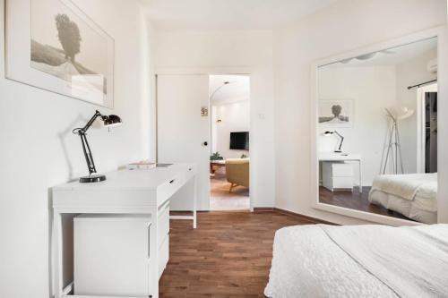 a white bedroom with a bed and a desk with a mirror at Ramat Hasharon Duplex Rooftop Oasis by Sea N Rent in Ramat Hash Sharon