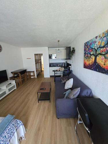 un salon avec un canapé bleu et une table dans l'établissement Charmant Studio au Cœur de La Grande Motte, à 2 min de la Plage, à La Grande Motte