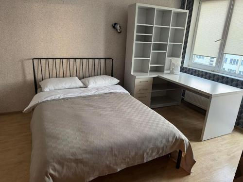 a bedroom with a bed and a desk and a window at Spacious&cozy south apartment in Šiauliai
