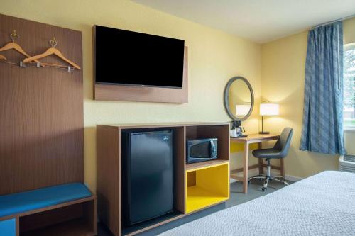 a hotel room with a tv and a bed and a desk at Days Inn by Wyndham Evansdale Waterloo in Evansdale