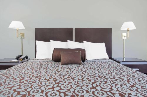 a hotel room with a large bed with two lamps at Days Inn by Wyndham Market Center Dallas Love Field in Dallas