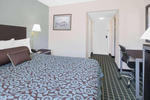 a hotel room with a bed and a desk at Days Inn by Wyndham Market Center Dallas Love Field in Dallas