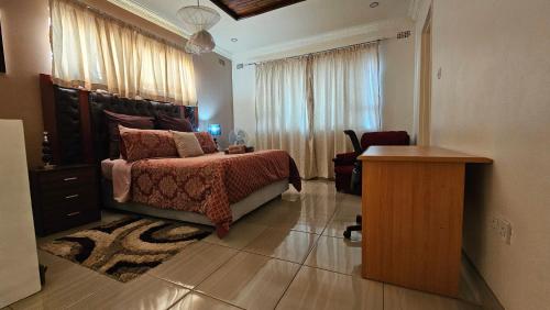 a bedroom with a bed and a dresser and a table at Grey Oak Holiday House in Bulawayo