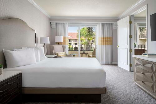 a bedroom with a large white bed and a living room at Hyatt Regency Huntington Beach Resort and Spa in Huntington Beach
