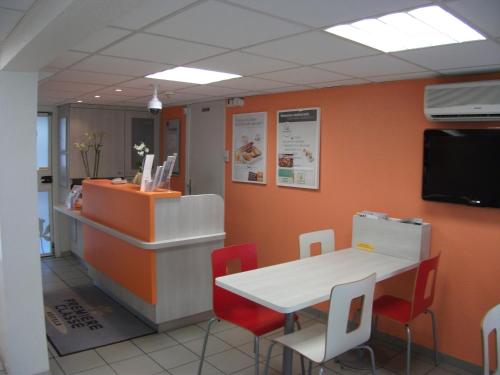 a waiting room with a table and red chairs at Premiere Classe Bayonne in Bayonne