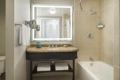 a bathroom with a sink and a tub and a mirror at Hyatt Regency Huntington Beach Resort and Spa in Huntington Beach