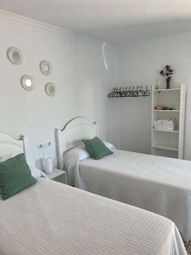two beds in a bedroom with white walls and green pillows at Alojamientos La Menúa in Los Badalejos