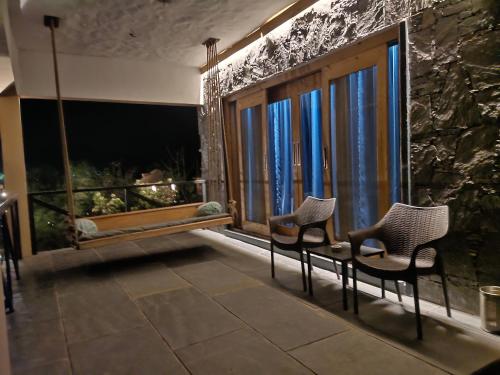 two chairs sitting in front of a room with windows at Bella Basera in Kumbhalgarh