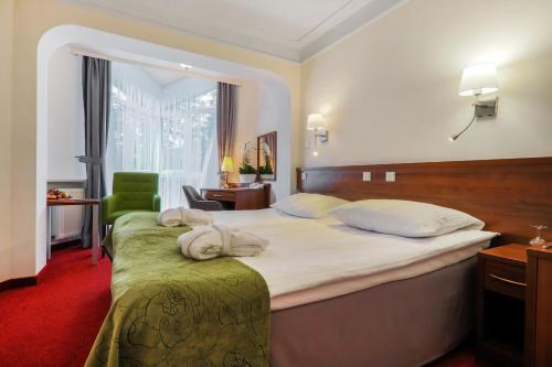 Pokój hotelowy z dużym łóżkiem i zielonym krzesłem w obiekcie Papuga Park Hotel Wellness Marrakesz & SPA w Bielsku Białej