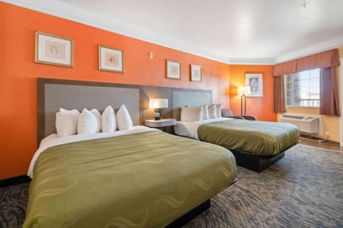 a hotel room with two beds and orange walls at Quality Inn & Suites Galveston - Beachfront in Galveston