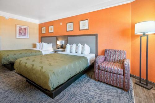 a hotel room with two beds and a chair at Quality Inn & Suites Galveston - Beachfront in Galveston