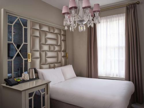 a bedroom with a large white bed and a chandelier at Henrietta House, a member of Radisson Individuals in Bath