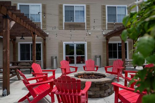 a patio with red chairs and a fire pit at Country Inn & Suites by Radisson, Queensbury - Lake George , NY in Lake George