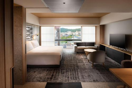 a hotel room with a bed and a couch and a television at Hilton Kyoto in Kyoto