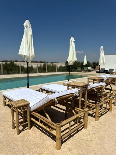 a group of tables and umbrellas next to a pool at Ciriga Sicily Glamping in Santa Maria Del Focallo