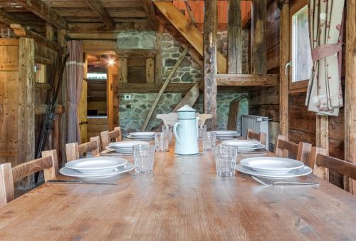 une longue table en bois avec des assiettes et des verres dessus dans l'établissement Le Gite - L'oréade - 6 pax, à Saint-Gervais-les-Bains