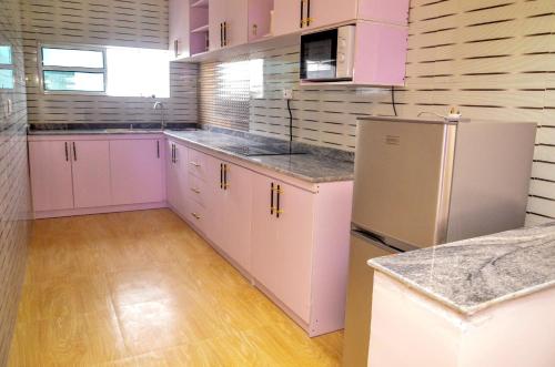 a kitchen with pink cabinets and a white refrigerator at Danag Apartments in Port Harcourt