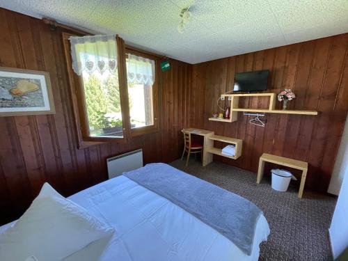 a bedroom with a bed and a desk and a television at Au Bivouac de Napoléon et Spa in Bourg-Saint-Pierre