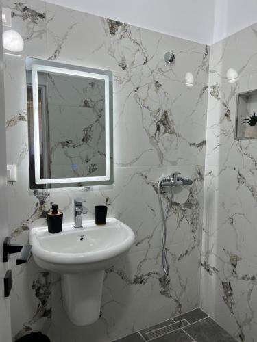 a white bathroom with a sink and a mirror at Nika's Guest House in Berat