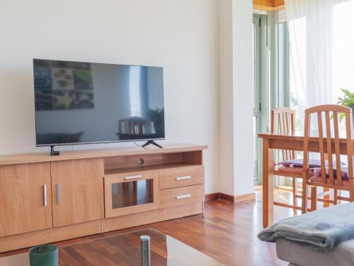 a living room with a flat screen tv on a wooden cabinet at BaruHaus piscina y parking Rianxo 1 in Rianjo