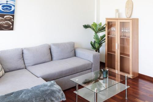 a living room with a couch and a glass table at BaruHaus piscina y parking Rianxo 1 in Rianjo
