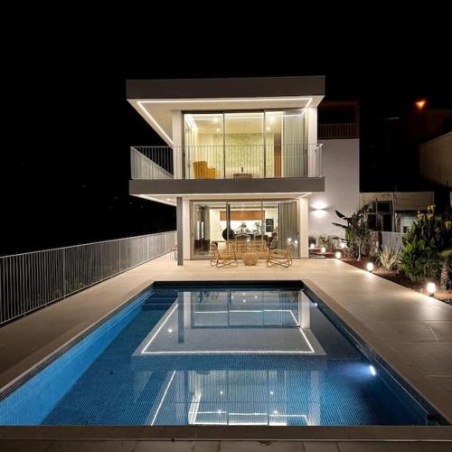 a swimming pool in front of a house at night at Cardais Paradise View in São Vicente