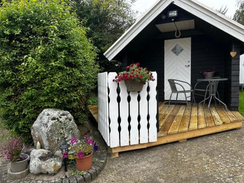 a small house with a white fence and flowers on a deck at Stunning Romantic Cabin close to Baltic see in Idestrup