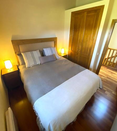 une chambre avec un grand lit blanc avec deux lampes dans l'établissement Casa adosada con piscina en Palau de Cerdanya, à Palau-de-Cerdagne
