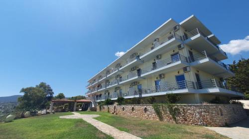 a large white building with a stone wall at De La Plage Hotel Koroni in Koroni