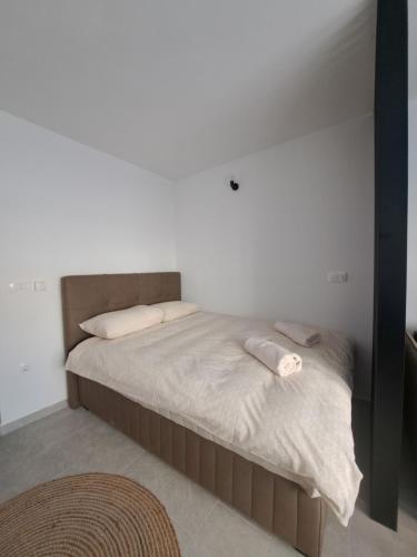 1 cama en un dormitorio con una pared blanca en Apartman Lamini, en Livno