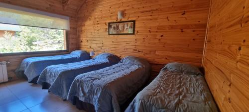 a room with three beds in a log cabin at Encanto del Rio in Villa La Angostura