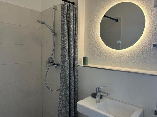 a bathroom with a shower and a sink and a mirror at Ferienwohnung Mühlbach in Breitbrunn am Chiemsee