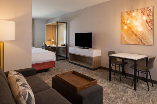 a hotel room with a couch and a bed and a television at SpringHill Suites by Marriott Turlock in Turlock