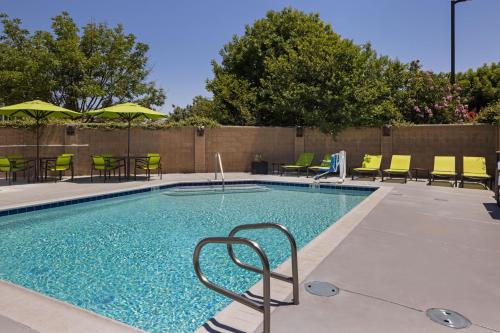a swimming pool with chairs and tables and umbrellas at SpringHill Suites by Marriott Turlock in Turlock