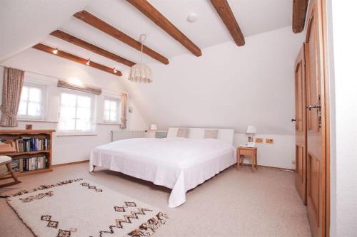 a white bedroom with a bed and a book shelf at Aurelia, Ferienwohnung in Schneverdingen