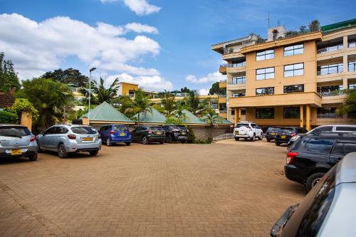Un estacionamiento con autos estacionados frente a un edificio. en Roswam Hotel, en Keruguya