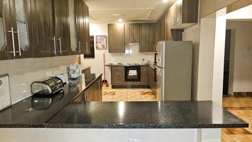 a kitchen with a black counter top and a refrigerator at Grey Oak Holiday House in Bulawayo