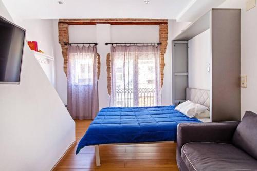 a bedroom with a blue bed and a couch at Apartamento con terraza privada cerca de la playa in Valencia