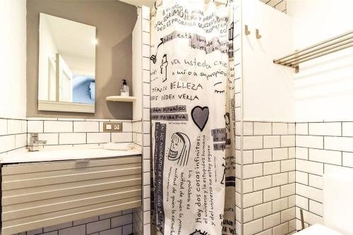 a shower curtain with writing on it in a bathroom at Apartamento con terraza privada cerca de la playa in Valencia