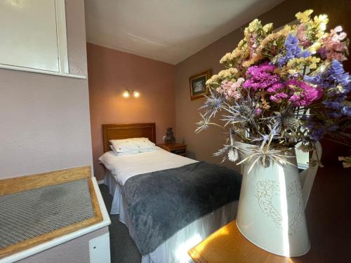 a vase of flowers on a table in a bedroom at The Prince of Wales in Huntingdon
