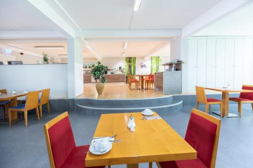 a dining room with a table and red chairs at Hotel Aviva in Leipzig
