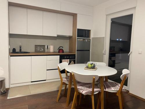 a kitchen with white cabinets and a table and chairs at LadyDi apartman in Banja Koviljača