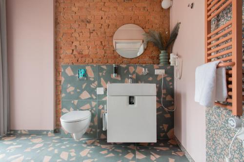 a bathroom with a toilet and a brick wall at Resume apartments in Kaunas