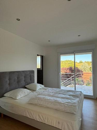 une chambre avec un grand lit et une grande fenêtre dans l'établissement La maison des Oliviers, 5min du ZooParc de Beauval, à Saint-Aignan