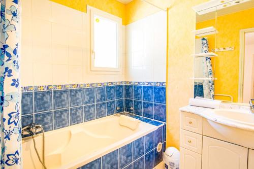 La salle de bains est pourvue de carrelage bleu, d'une baignoire et d'un lavabo. dans l'établissement Villa Louis by Villa Plus, à Les Adrets-de-l'Estérel