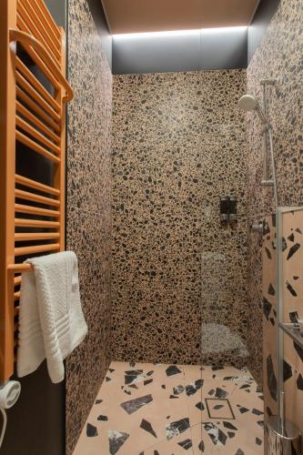 a bathroom with a shower and a tile wall at Resume apartments in Kaunas
