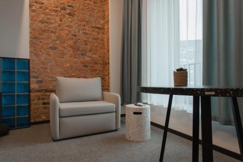 a chair and a table in a room with a brick wall at Resume apartments in Kaunas