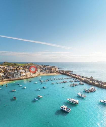 an aerial view of a harbor with boats in the water at "SMUGGLERS HIDE" & "SMUGGLERS CABIN" - A 2 Bedroom FISHERMANS COTTAGE with Childs Bunk and HARBOUR VIEWS - and also a private entrance connecting 1 BED STUDIO - 10 Metres To Sea Front - 2023 GLOBAL REFURBISHMENT AWARD WINNER in St Ives